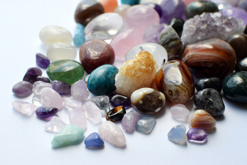 Tumbled gems of various colors. Amethyst, rose quartz, agate, apatite, aventurine, olivine, turquoise, aquamarine, rock crystal on white background.