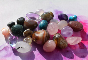 Gemstones of various colors. Amethyst, rose quartz, agate and rock crystal on a pink watercolor background