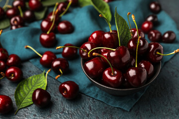 Bowl of ripe cherries on dark color background