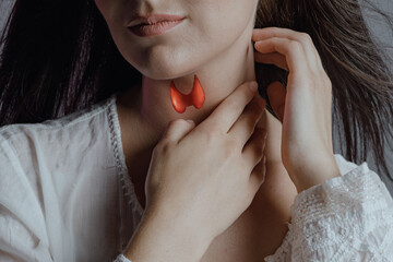 A woman examines the thyroid gland. A virtual thyroid gland is drawn in red on the neck.
