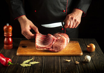 Butcher cuts raw ribs on a cutting board before preparing a meat dish. Hotel Recipe Idea