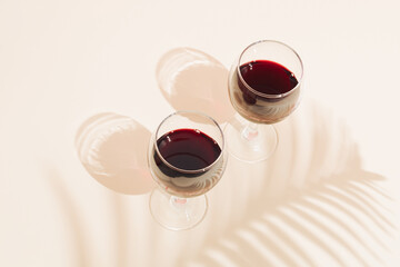 Two glasses of red wine with a shadow of a palm leaf. Valentine's Day or Love concept.