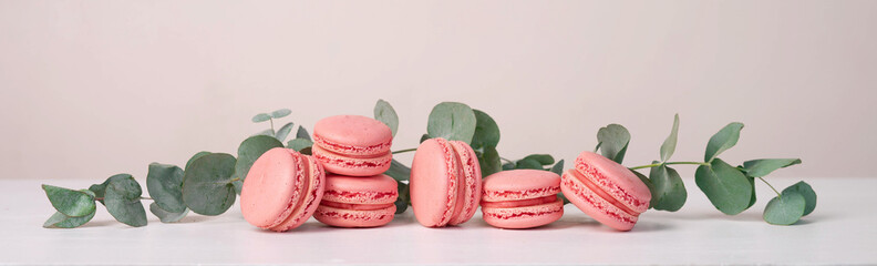 Pink macaron cookies on a beige background. Header with a traditional French dessert.