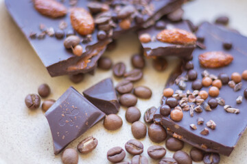 Chopped dark chocolate with almond and coffee beans. Broken chocolate on beige plate. Sweet food. Dark chocolate iwith nuts. Coffee product. 