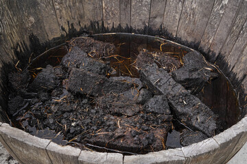 Wet lumps of peat in front of a whisky distillery. After the peat is dried it is used to dry the...