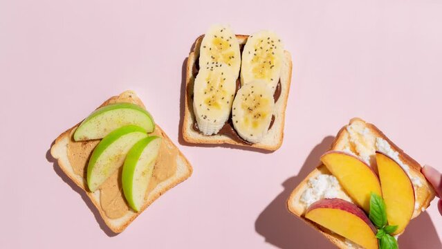 Set of toasted bread with peach, apple and banana on pink background. Stop Motion Animation.