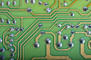 Back of green printed circuit board  with copper traces and solder dots