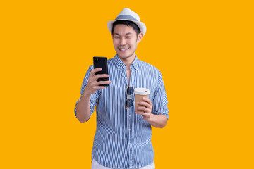 casual traveller male adult wear hat  relax leisure hand hold coffee cup standing while smartphone checking booking flight and hotel online reserve smart travel application online platform studio shot