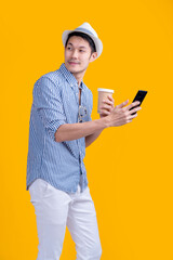 casual traveller male adult wear hat  relax leisure hand hold coffee cup standing while smartphone checking booking flight and hotel online reserve smart travel application online platform studio shot