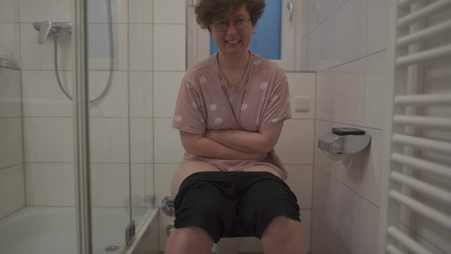 Sick unwell woman holding stomach, suffering from diarrhea, constipation and cystitis in toilet. Abdominal pain during menstruation. Concept of health care and pain. Woman in bathtub with hurt abdomen