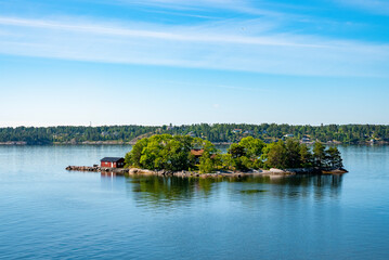 Fototapeta premium Idyllic scenery of houses on island against blue sky. Picturesque scenery of Archipelago in Baltic Sea. View of Swedish lifestyle with beautiful natural landscape.