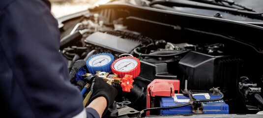 Close up hand of auto mechanic using measuring manifold gauge check the refrigerant and filling car air conditioner for fix and checking for repair service support maintenance and car insurance.