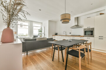 Interior of spacious light dining room with fireplace and elegant chandelier located near kitchen...
