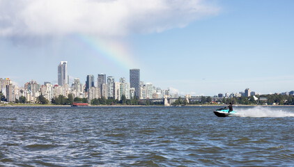 Obraz premium Adventurous Caucasian Woman on Water Scooter riding in the Ocean. Modern City in background. Downtown Vancouver, British Columbia, Canada. Colorful Rainbow