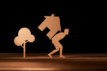 Representation in cut cardboard of a man carrying a house on his back. Rising house prices, high...