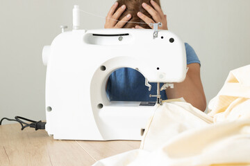 A woman works on a sewing machine. To spoil, to make.