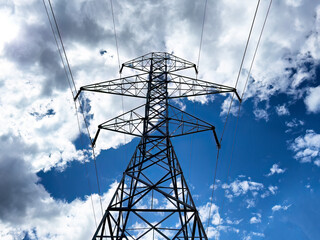 Tower holding electric power lines with clouds and blue sky