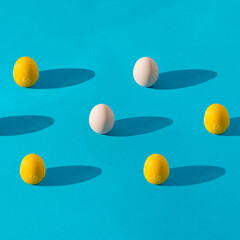 egg yolk and whole egg pattern on blue background with long shadows. Healthy food concept, square composition with copy space.