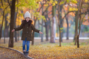 Happy girl playing in autumn park. Beauty nature scene with family outdoor lifestyle. Happy girl having fun outdoor. Happiness and harmony in childhood