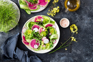 Fototapeta na wymiar Spring salad with radish, cucumber, lettuce and mustard flowers