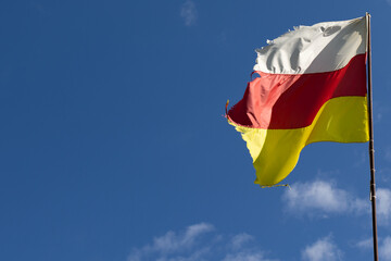 Old flag, blue sky background. Republic of North Ossetia Alania. South Ossetia.