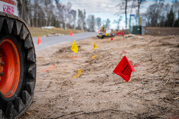 A small flag warning of an underground line at a construction site, with other flags, out of focus in the distance. Shallow depth of field focus with bokeh.