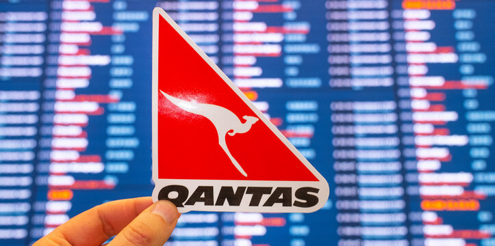 December 11, 2021, Sydney, Australia. The emblem of Qantas Airlines against the background of an electronic scoreboard with flight schedules at the international airport.