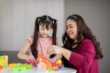 Fototapeta premium Young mother playing toy with daughter in a home., Happy and relaxing time.