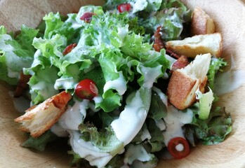 Fresh tomatoes with cucumber, lettuce, red onion and spices in a white bowl. 