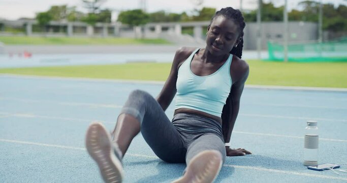 Fit woman stretching her legs and touching her feet for a warmup to prevent injury on a sports track. Happy young african american athlete preparing her body and muscles for a cardio training workout