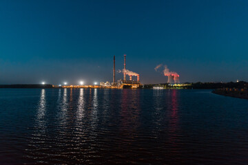 A night view of the lake, in the distance the illuminated chimneys of a coal-fired power plant.