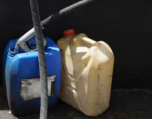 two dirty plastic gasoline Jugs. Plastic canister for fuel with filling hose gun.