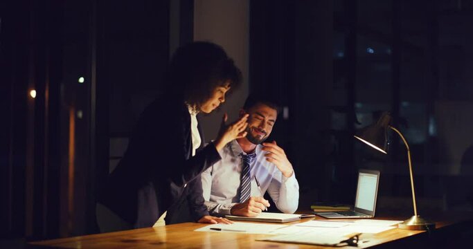 Young lawyers working on paperwork for a legal case. Collaborating to plan a strategy in a corporate startup law firm. Two business people analyzing paperwork and using laptop at night in an office