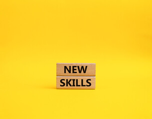 New skills symbol. Wooden blocks with words New skills. Beautiful yellow background. Business and New skills concept. Copy space.