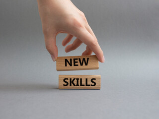 New skills symbol. Wooden blocks with words New skills. Beautiful grey background. Businessman hand. Business and New skills concept. Copy space.