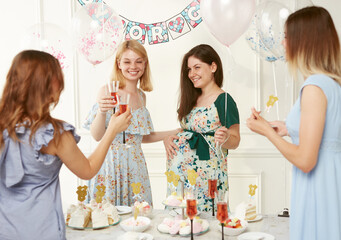 Happy women celebrating together during the genre reveal the party, over balloons background.