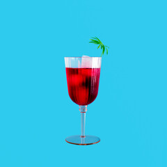 Cocktail glass, fruity drink, ice cubes, tropical decoration. Bright ocean blue background. Summer holiday minimal concept. 