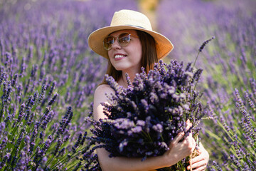 A young woman in a straw hat with a bunch of lavender flowers.