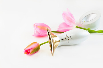 microcurrent massager on a white background with pink tulips. High quality photo