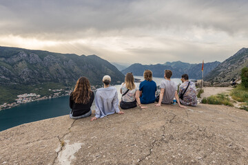 grupo de pessoas contemplando o pôr do sol com vista para montanhas em Kotor, Montenegro. © Mateus R Fiuza