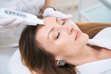 Woman in the cosmetology center on the procedure of ultrasonic facial cleansing