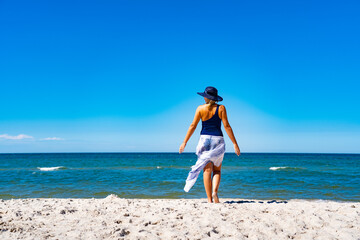 Woman walking on sunny beach
