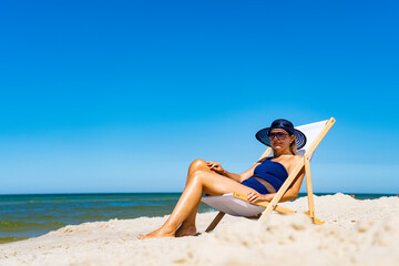 Obraz na płótnie Canvas Woman relaxing on beach sitting on sunbed 