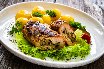 Stuffed pork minced meat with mushrooms, potatoes and greens on wooden table
