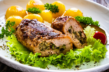 Stuffed pork minced meat with mushrooms, potatoes and greens on wooden table
