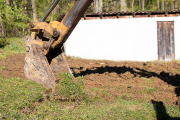 An bucket excavator in the village paves the way, digs soil and clears land.