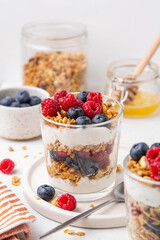 Granola with yogurt in glass served with fresh raspberry, blueberry and honey. Homemade oatmeal muesli. Vegetarian breakfast, healthy eating concept. Selective focus.