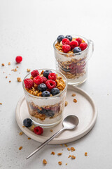 Granola with yogurt in glass served with fresh raspberry, blueberry and honey. Homemade oatmeal muesli. Vegetarian breakfast, healthy eating concept. Copy space. Selective focus.