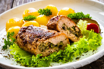 Stuffed pork minced meat with mushrooms, potatoes and greens on wooden table

