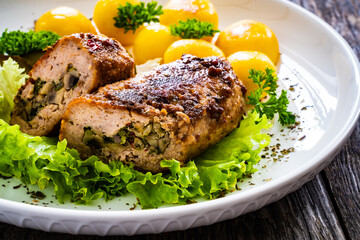 Stuffed pork minced meat with mushrooms, potatoes and greens on wooden table
